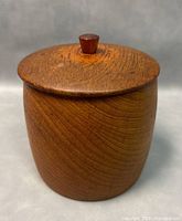 Ice bucket closed showing cylindrical teak wood container with lid and knob.