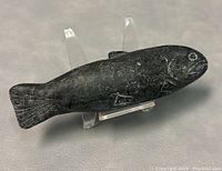 Front angle view of the dark soapstone fish carving, showing detailed incised fins, eye, and overall shape.