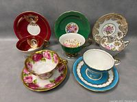 Photo showing five porcelain tea cup and saucer sets with distinct designs and floral patterns