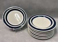 Stack of seven small dessert plates with blue circle design on white background, showing overall condition and quantity.