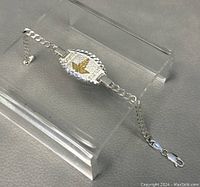 Full view of 7-inch sterling silver ID bracelet with gold tone eagle design on textured oval plate and curb chain with lobster clasp.