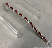 Close-up of silver link bracelet with red enamel segments, showing clasp and link detail