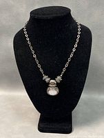 Front view of 925 silver necklace with pierced pendant on black display stand.