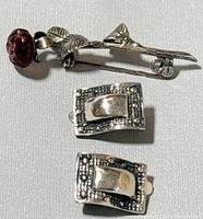 Photo showing the silver Victorian rose brooch with a dark reddish-orange stone and the pair of clip-on earrings with raised rectangles and textured detailing, all marked 925 silver.