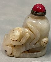 Side view of the snuff bottle showing carved monkey details and red cap