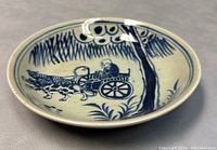 Angle view showing the hand-painted design of an elderly man in a chariot pulled by two animals, crackle glaze and minor wear on rim.