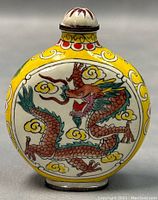 Front view of the enamel snuff bottle showing red dragon on a yellow background with decorative flowers and clouds.