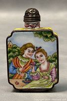Front side of the snuff bottle showing two women in historical dress holding flowers with greenery background.