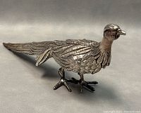 Left-front view showing detailed feather engraving, body, legs and tail structure.