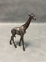 Front angle showing giraffe sculpture detail and patina