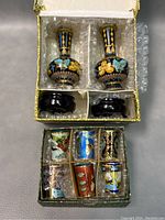 Top view of the set boxed: two cloisonné bud vases with wooden bases in one compartment; six Russian embossed cloisonné cups in another