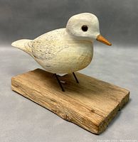 Side angled view showing the bird's carved details, paint, and wooden base texture.