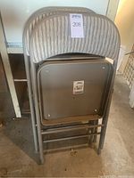 Three stacked Samsonite metal folding chairs showing backs with striped fabric upholstery.