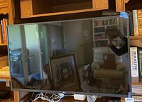 Front view of LG 43" UHD TV placed on a wooden shelf, screen is off reflecting room interior.