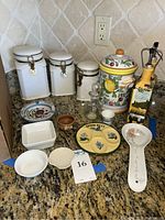 Overview of all items including canisters, spoon rests, bowls, cruet set, ashtray, and cups on granite counter.