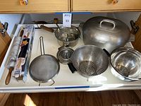 Full set of kitchen items including Wagner Ware roaster, colander, mixing bowl, ricer, strainer, citrus juicer, marble rolling pin, and Pampered Chef rolling pin in box.