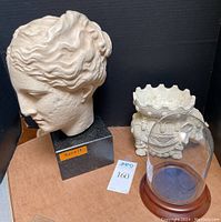 Frontal view of bust head of Greek Goddess Hygieia on black marble base with painted resin elephant and glass dome display case to the right, with auction lot number 160 visible