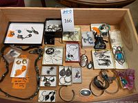 Tray of assorted jewelry including gold earrings, pendants, brooch, and multiple sterling silver rings, earrings, necklaces.