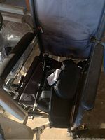 Close-up photo of the transport wheelchair seat and armrest showing fabric and footrest area