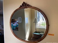 Front view of oval mirror showing carved wooden frame and reflective beveled glass