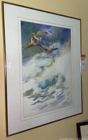 Framed watercolor painting showing pelicans flying over ocean waves with a mat and simple frame.