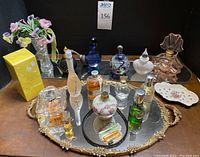 Full assortment of perfume bottles, holders, trays, vase with beaded flowers, Haviland Limoges trinket dish, and black heated hairband on mirrored surface