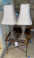 Pair of gold tone beaded shade lamps sitting on metal and glass side table.