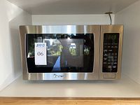 Front view of the Magic Chef stainless steel microwave oven showing control panel and window door.