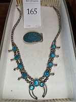 Overview of squash blossom necklace and belt buckle in tray