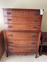 Front view of the 6-drawer wooden tall dresser showing bow front design and antique brass oval pull handles.