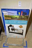 Front of the EZ Adjust Bedrail box featuring an image of the product with a child sitting on the bed, including one wrapped extra part in front.