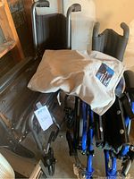 Folded Invacare wheelchair with transport wheelchair beside it, beige Medline Comfort Glide repositioning sheet placed on top.
