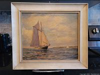 Frontal view of the old original oil painting showing sailboat with sails up on calm water under a cloudy sky with distant land visible.