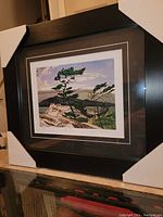 Front angled view of the professionally framed AJ Casson fine art print "White Pine", showing the tree, mountain, and sky in the artwork, with white corner protectors on the frame.