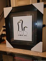 Framed fine art print featuring three stylized Canada geese, set in a black frame with white mat and protective corner covers.