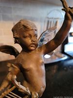 Close-up of cupid’s head and upper torso showing facial features and patina wear