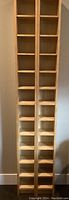 Front view of tall blonde pressed wood cubed shelving unit with two columns of 6" square compartments.