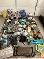 Overview of gardening lot showing hoses, gloves, seat, and various supplies arranged on the floor.