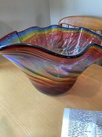 Front angle of Dan Bergsma handblown glass bowl showing wavy rim and rainbow swirl.