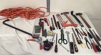 Full view of assorted hand tools and extension cord laid on a white surface showing all items