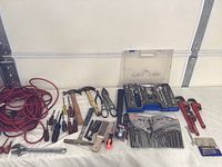 Various hand tools arranged on table including hammers, screwdrivers, files, hand saw, scissors, and coiled extension cord