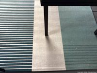 Top view of the rug showing teal, beige and green blocks and stripes under a dining table.