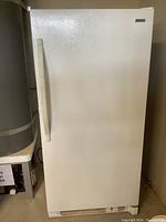 Closed view of the white Kenmore upright freezer showing the large handle and textured finish.
