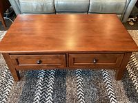 Front view of closed lift-top coffee table on rug in front of sofa