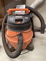 Ridgid 14 gallon shop vacuum showing front view with attached hose and handle.