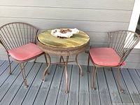 Full view of the bistro set with table, two chairs with cushions, and driftwood on the table.