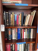 Photo showing multiple history and novel books on a wooden bookshelf, various titles visible, condition shows some wear.