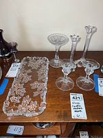 Photo showing all glass candle holders and decorative glass tray on a wooden surface with lot tags.