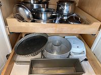 Drawer containing tart pan, angel food cake pan, rectangular loaf pan, and Oster waffle maker in white.