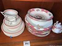 Full view of stacked plates, tea cups, and sugar bowl showing floral pink and gold Lady Carlyle pattern